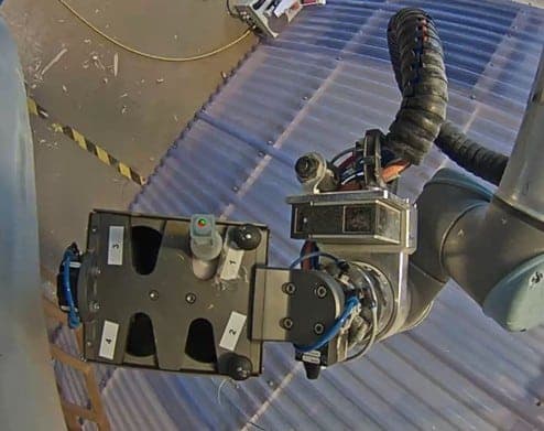 Close-up of the Rope Robotics manipulator arm clamped to a turbine blade surface, ready to perform inspection.